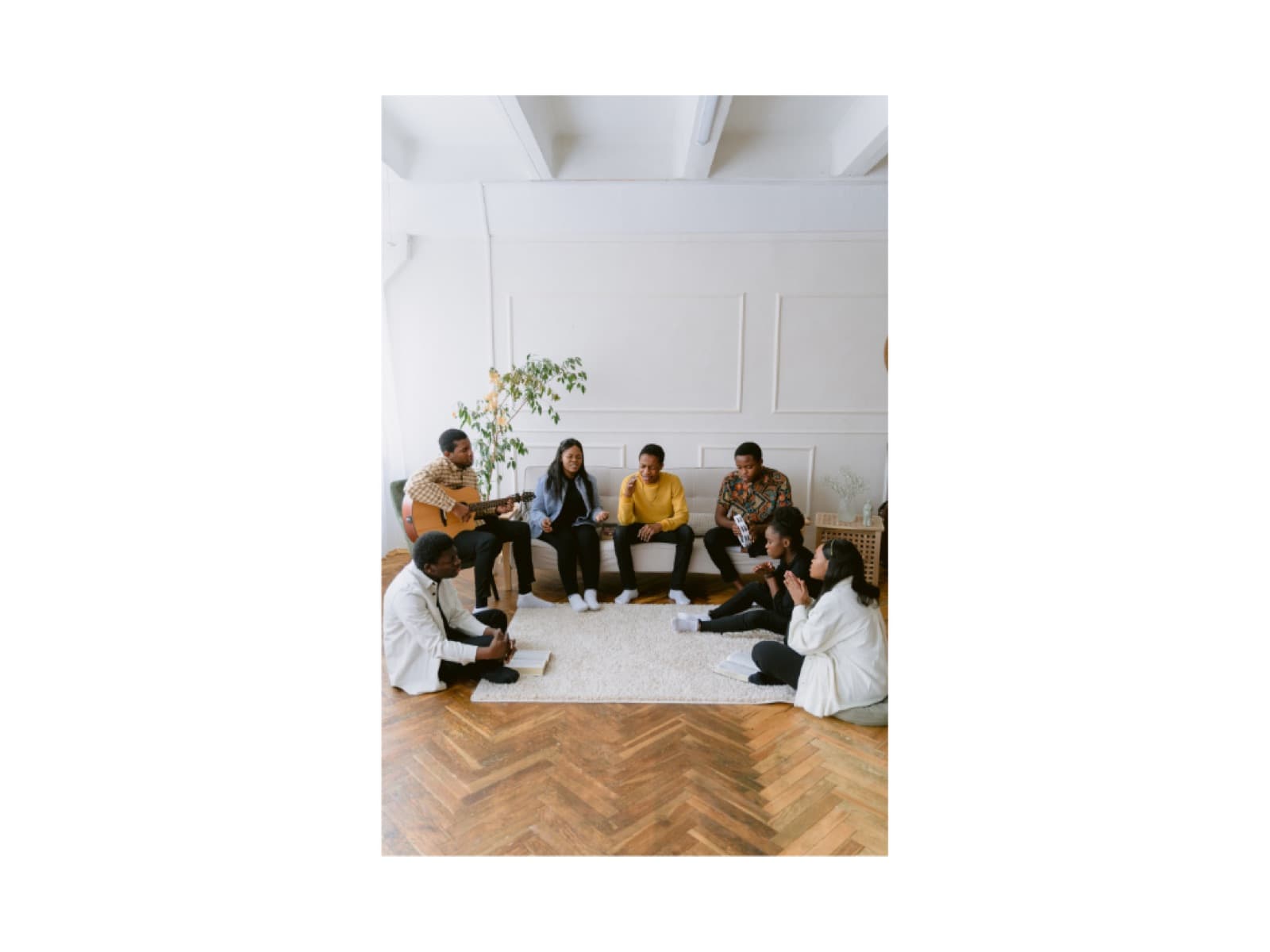 Friends gather in a warm living room, talking and playing music.